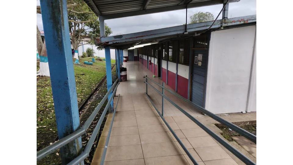 Covered school walkway with classrooms and a grassy courtyard.