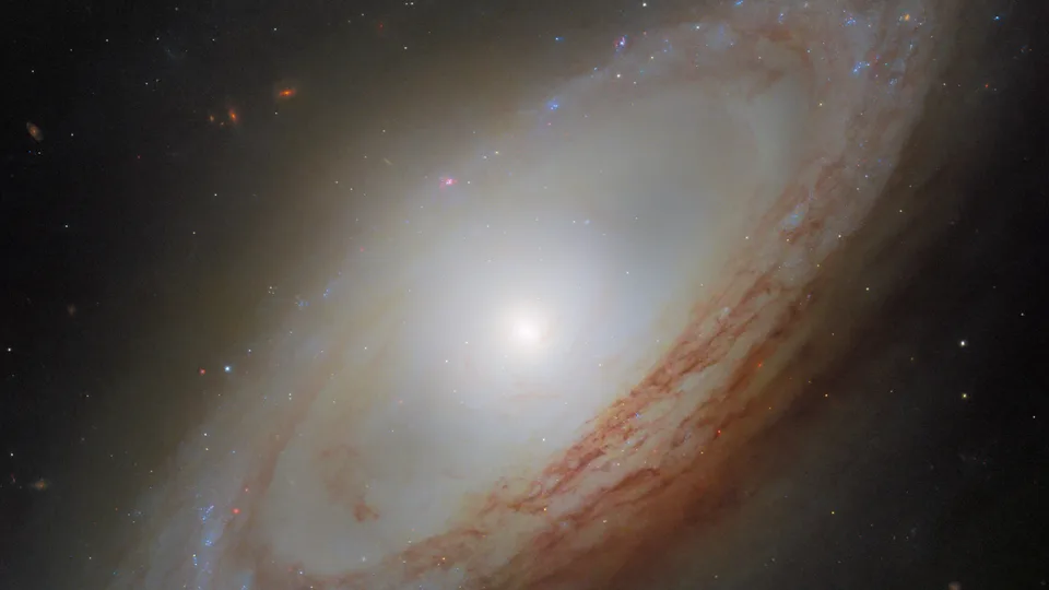 Яскравий світлий центр NGC 4698, темні пилові смуги та блакитні зоряні ділянки у нахиленому диску.
