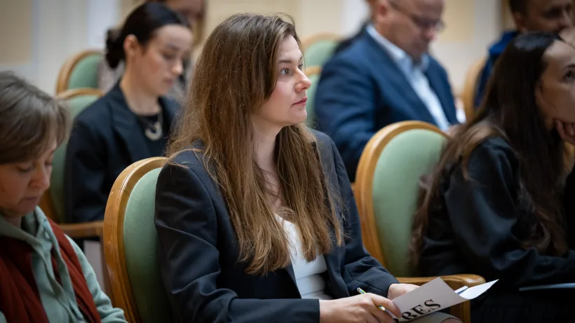 Учасниця зустрічі тримає папери на колінах.